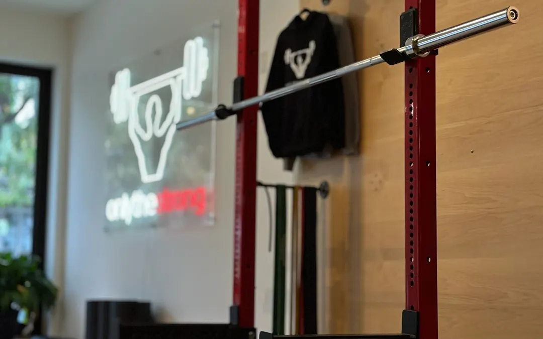 The Leslieville studio: a lifting rack, warm wood and the neon onlythestrong sign